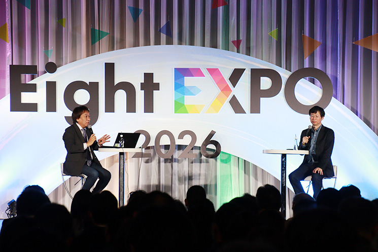 イベント『Eight EXPO 2026』で行われた特別講演「人とAIが共創する未来へ」の様子。向かって左側に日本マイクロソフトの西脇資哲氏、右側に日立製作所の吉田順氏が座り、対談を行っている。会場には多くの来場者が詰めかけ、両氏が生成AIの真の実装と組織の知性拡張について議論を交わす、熱気あるセッションの全体風景。