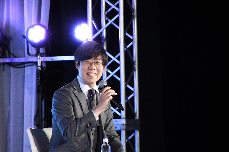 イベント『Eight EXPO 2026』で講演する、サンリオエンターテイメント取締役の木原健太郎氏。 マイクを手に、AIによる動員予測と現場の熱狂の乖離について解説しているシーン