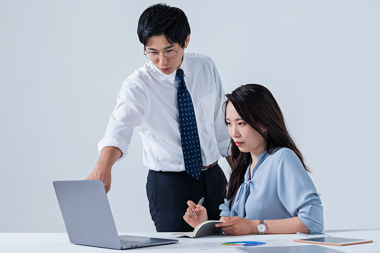 オフィスでチームメンバーがタブレットを囲み議論する様子。エンジニア出身マネージャーが直面する「コードは書き換えられるが他人はコントロールできない」という現実と、強い言葉での強制が招く不快な状況からの逃避行動、そして自発的なマインドを引き出す重要性を対比的に示す文脈で使用