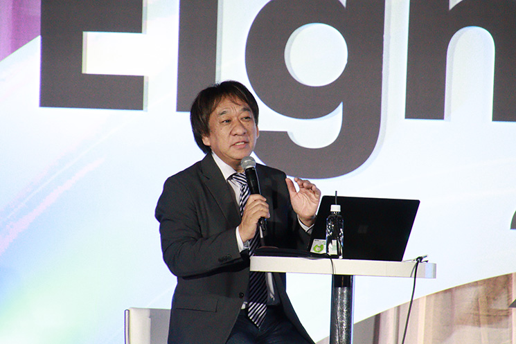 ビジネスイベント『Eight EXPO 2026』にて、生成AIの戦略について講演する日本マイクロソフトのエバンジェリスト・西脇資哲氏。西脇氏はマイクを手に、生成AIの3年間の利用の積み重ねとデータの重要性について身振り手振りを交えて熱弁している。