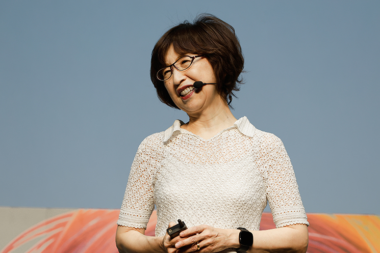 DeNA AI Day 2026にて、AIエージェント「デモン君（OpenClaw）」との仕事を笑顔で語る南場智子会長。Slackを通じてToDo管理やリマインドを自律的に行うAIスタッフとの共創や、時には思い通りにいかず「喧嘩」をすることもあるという、人間とAIが日常的に対話しながら業務を進める次世代の労働環境の実態を伝えている