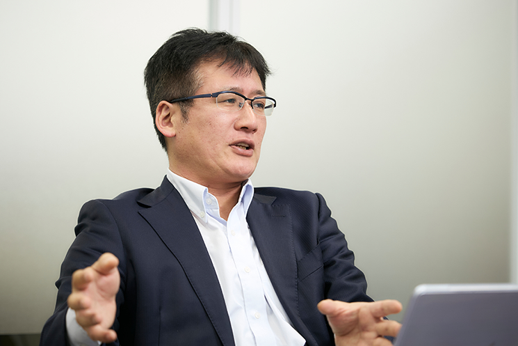 「エンジニアの技術空洞化」を料理に例えて解説する西島正憲氏。ボタン一つで料理ができる自動調理器（現代のクラウドやAI環境）の利便性を認めつつも、一流のシェフが素材や火加減を熟知するように、OS、ネットワーク、サーバー、アプリという全レイヤーの「仕組み」を深く理解することこそが、高品質なシステムを作るプロの条件であると説いている