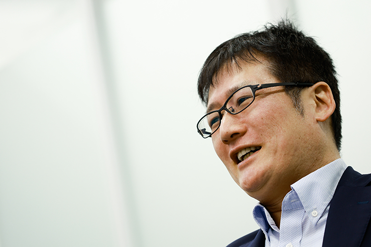 若手エンジニア時代の自由な試行錯誤を語る西島正憲氏。ウイルス感染やOS初期化を経験しながら技術を磨いた過去と、コンプライアンスや規制の強化により「リスクを伴う挑戦」が困難になった現代の対比を示している。社会の安定と引き換えに、エンジニアがマニアックなスキルを追求し「野生の思考」を養う機会が失われている現状を指摘する一幕