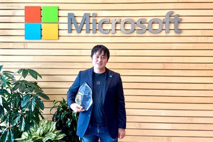 界3,000人の中のトップスピーカー賞（Distinguished Speaker Award）を受賞し、記念トロフィーを片手に記念撮影をしている吉田さんの様子。