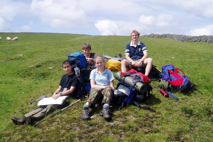 イギリスの草原で友人とトレッキングをしている学生時代の吉田さんの様子