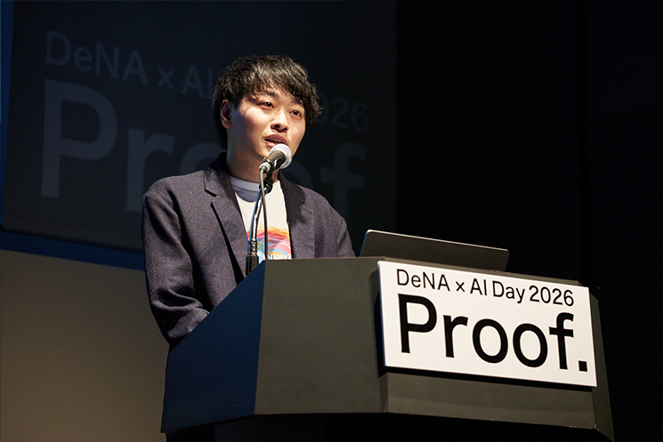 「DeNA × AI Day 2026」の終盤、今後の展望について語る石井敬時氏。指数関数的に変化する世界において、自らの取り組みさえも「来年には古い」と言い切る覚悟を示している。正解のない問いに対し、AIという相棒と共に変化を面白がり、自らの思考をアップデートし続けられる人材こそが必要であるという、DeNAの採用哲学と未来への強い意志が込められた締めくくりのショット。