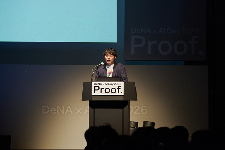 「DeNA × AI Day 2026」にて、AI活用が進む中での「人間の役割」について熱弁を振るう石井敬時氏。AIが過去のデータに基づき論理的な判断を下す一方で、人間が候補者の心を動かす「情緒的な化学反応」や「納得感の構築」に専念する重要性を強調。判断の根拠をAIに託すことで、人事が候補者の人生に深く入り込むという、アナログで泥臭いコミュニケーションの価値を再定義する象徴的な一幕。