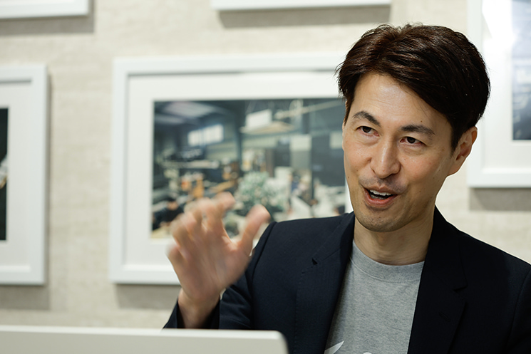 freee株式会社CISOの茂岩祐樹氏が、Mobage（モバゲー）時代のネットワーク機器選定における「カタログスペックの罠」を解説するシーン。通信速度（Mbps）の数値に騙されず、ガラケー特有の小さなパケットサイズが引き起こす秒間パケット処理数（pps）の上限ボトルネックを見抜いた経験から、システムの設計思想や前提条件を多角的に検証する重要性を説くカット。