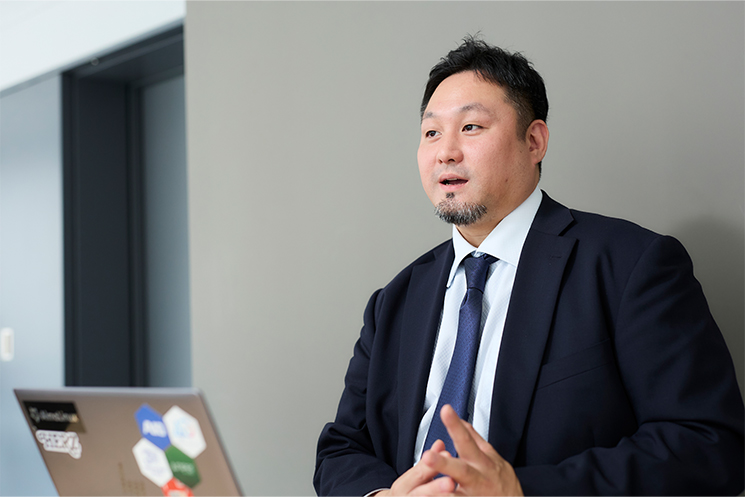 プラウドアドバンスの村上さんが、ネットワークやインフラの世界における運用保守業務の奥深さについて語っている様子。