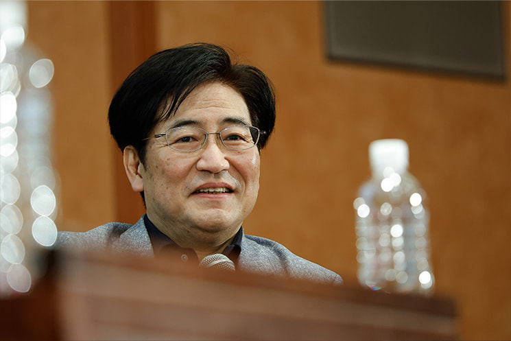 東京大学の最終講義の締めくくりにて、東大着任当初に入試希望者が誰も来なかった静かな始まりから一期生の玉城絵美氏との出会いを経て、世界の第一線で活躍する数々の素晴らしい学生たちに恵まれた19年間の幸運に心からの感謝を述べ、満面の温かい笑顔を見せる暦本純一教授