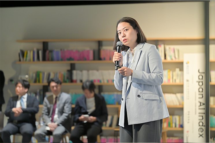 2026年6月の「Japan AI Index」発表会にてマイクを手に語るPKSHA Technology CEO室室長の大野紗和子氏。自社の固有知識を獲得したAIエージェントが、要件定義書から設計書作成、コード実装、テスト実行、本番移行まで開発プロセス全体に横断的に伴走する仕組みを解説し、企業の厳しいセキュリティ要件を満たすプライベート環境と人による組織・文化醸成支援が実装条件であると示している