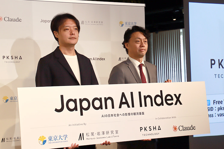 2026年6月4日、PKSHA Technology、東京大学松尾・岩澤研究室、Anthropicの3者連携記者発表会にて「Japan AI Index」のボードを掲げるPKSHAの上野山勝也氏ら登壇者。国内の膨大なClaude利用動態データと公的統計を突き合わせ、AIが雇用や産業に与える影響を完全に視覚化するインフラプロジェクトの発足を示している