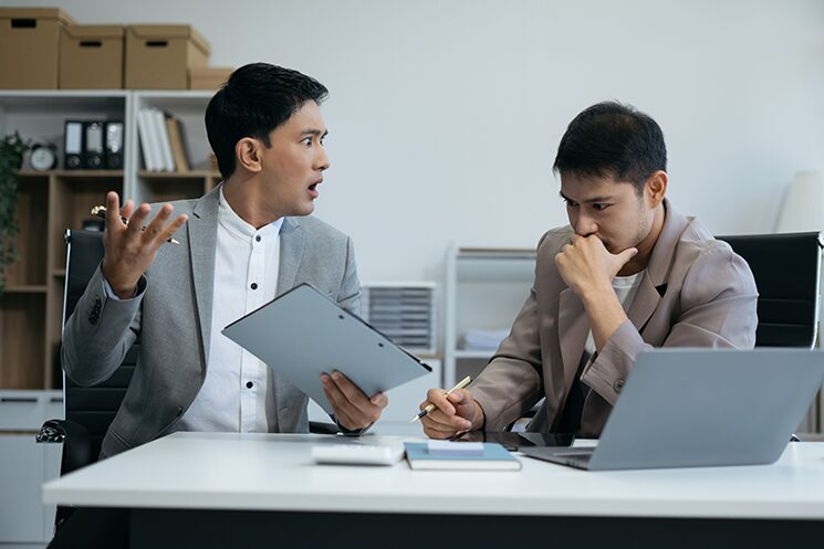 自身の意見を押し通そうとする男性と、議論をあきらめている男性のイメージ写真
