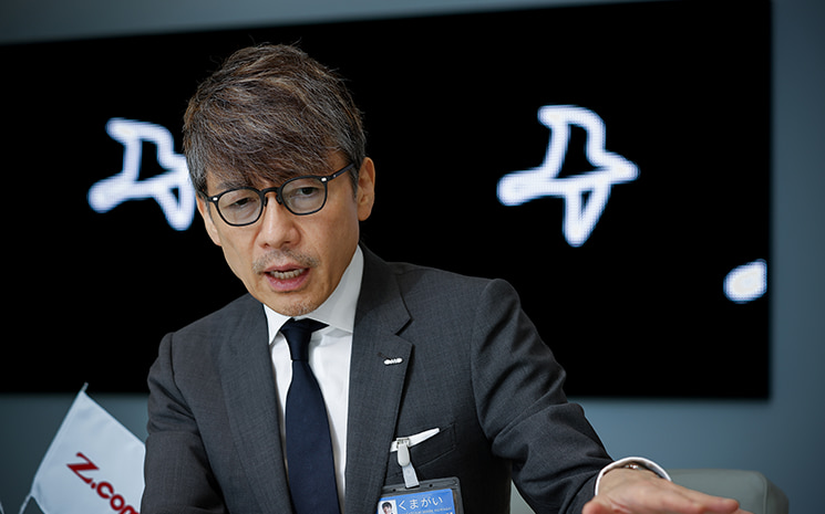 AIによって効率化され生み出された「浮いた時間」の価値について、手を前に差し出しながら強い眼差しで語るGMOの熊谷正寿氏。誰しも「命のカウントダウン」は始まっており、毎朝自作アプリで秒単位で削られる平均余命を確認しているからこそ、他人の作った正解で時間を浪費せず、リアルな危機感を持って自分の人生をコントロールすべきだと説くシーン