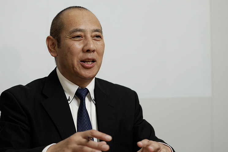 身振り手振りを交えて笑顔で語るインフォース代表取締役の濱松毅氏。自社ツールの高い変換精度が認められ、米国マイクロソフトの次期製品を先行開発するTAP（Technology Adoption Program）チームへ参加することになった経緯と、実績主義な現地での評価に対する所感を明かす場面