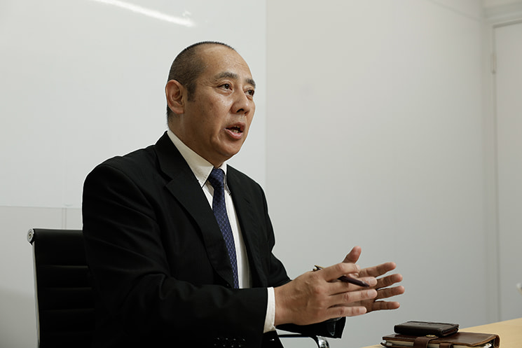 手を動かし真剣なまなざしでキャリアと思想を明かすインフォース代表取締役の濱松毅氏。iモード等の失敗例を引き合いに技術トレンド追随の怖さを語り、30年前から現在まで現場で使われ続けるMicrosoft Accessの事例から「流行ではなく課題解決に軸を置くエンジニアの生き残り戦略」について主張する場面