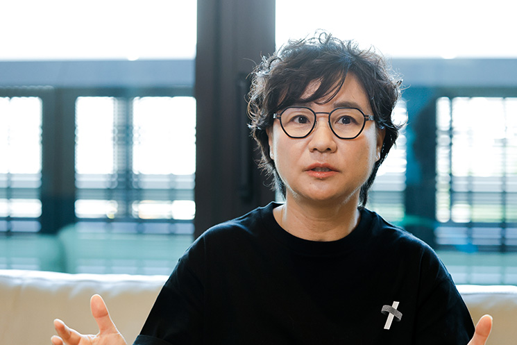 LINEヤフーのCTO・朴イビンさんが、数十年分のレガシーシステムや仕様書の構造化、SSOT（単一の正しい情報源）の再構築について、身振りを交えて語るインタビューカット