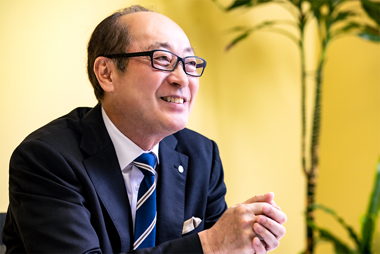 眼鏡をかけ、穏やかな笑みを浮かべて語るサイゼリヤ代表取締役社長の松谷秀治氏。入社当時は出世欲ばかりだった自身を変えた現会長の「人生の51パーセントを世の中のために尽くせる人を目指しなさい」という言葉と、その後の経営において「客のためと言いつつ自分のためになっていないか」と自問自答する原点を象徴するポートレート