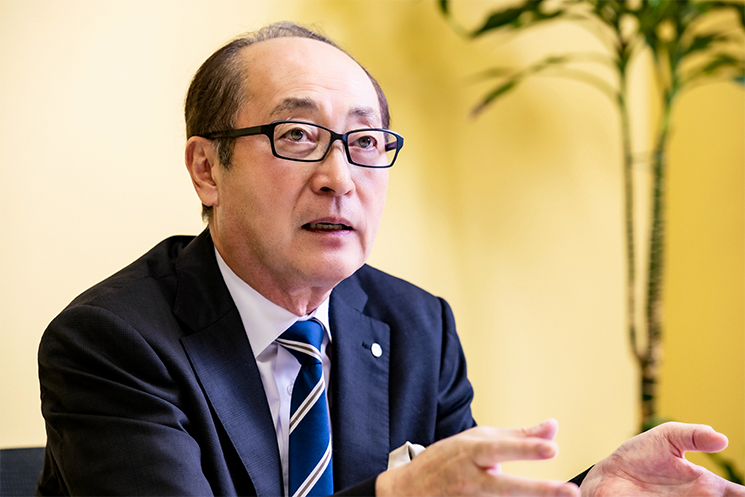 身振り手振りを交え、真剣な面持ちで語るサイゼリヤ代表取締役社長の松谷秀治氏。原材料費やエネルギー価格が高騰する中でも「価格据え置き」を宣言した背景にある、人々の暮らしを豊かにし、誰もが気軽に外食を楽しめる社会を提供するという同社の存在意義と経営理念を象徴するポートレート