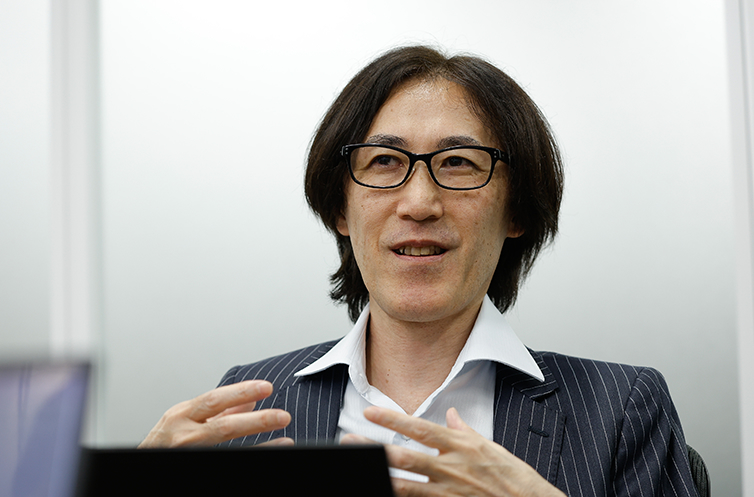 基板設計専門学校を経て8ビットパソコンの設計からハードウェア、プログラミング、ネットワーク、サーバーと領域を拡げてきたセキュアエッジの小原氏。IT技術の変化に伴い自らの専門性を拡大させてきた経験と、インフラエンジニアとしての基礎形成の歩みについて身振り手振りを交えて語る姿